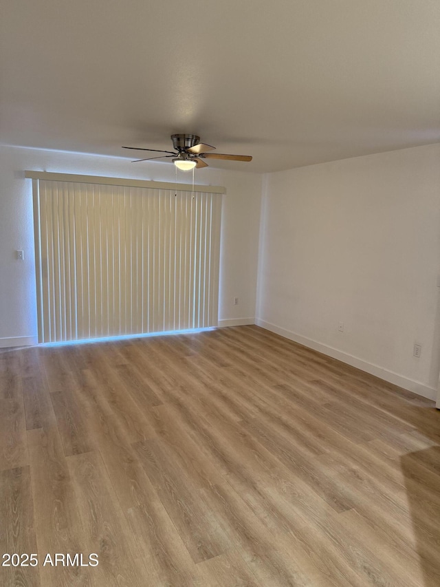 spare room with ceiling fan, light wood-type flooring, and baseboards