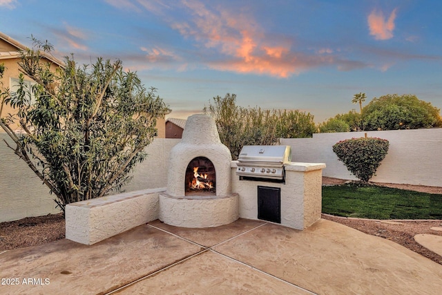 3037 E Bighorn Ave, Phoenix, AZ 85048 - patio terrace at dusk with a grill, a lit fireplace, area for grilling, and fence