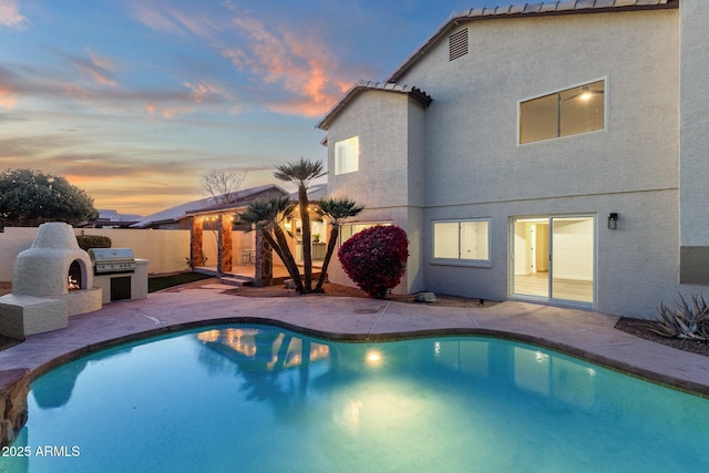 3037 E Bighorn Ave, Phoenix, AZ 85048 - pool at dusk with a fenced in pool, a patio, area for grilling, a lit fireplace, and fence