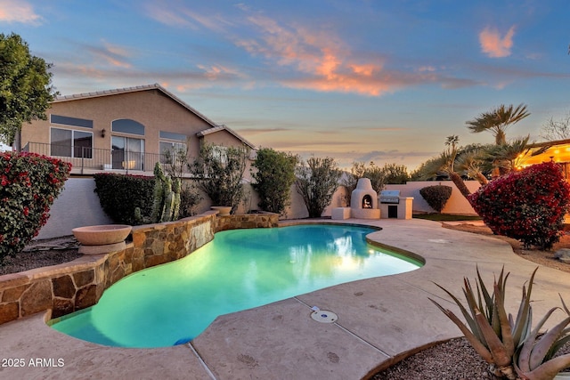 3037 E Bighorn Ave, Phoenix, AZ 85048 - pool at dusk with a fenced in pool, a fireplace, and a patio