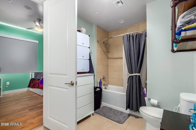 bathroom featuring shower / bathtub combination with curtain, ceiling fan, tile patterned flooring, washer / clothes dryer, and toilet