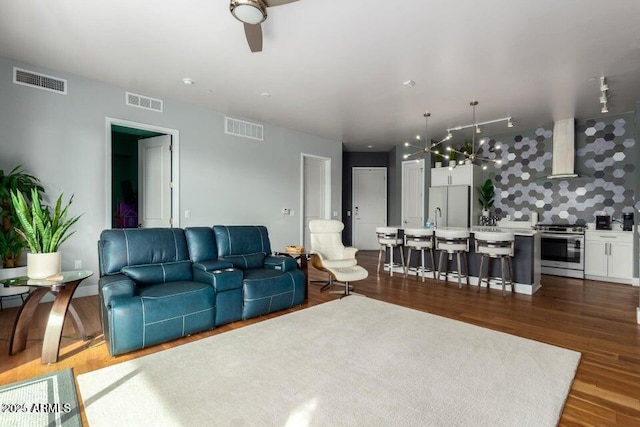 living room featuring dark hardwood / wood-style flooring and ceiling fan with notable chandelier