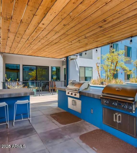 view of patio / terrace featuring a bar, an outdoor kitchen, and area for grilling