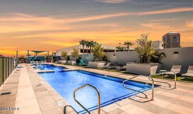 pool at dusk featuring a patio area