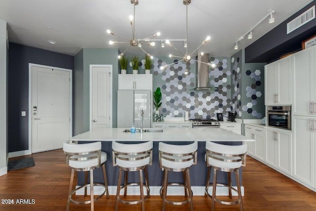 kitchen with a large island, stainless steel oven, white cabinets, and wall chimney exhaust hood