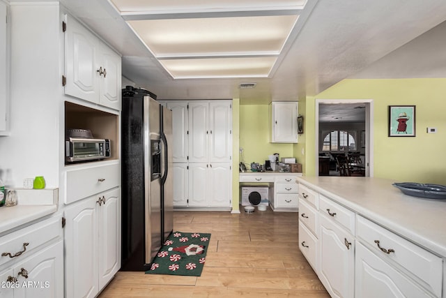 kitchen featuring stainless steel fridge with ice dispenser, white cabinets, and light wood-type flooring