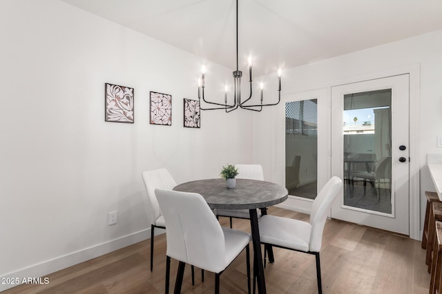 dining room with baseboards, light wood finished floors, and an inviting chandelier