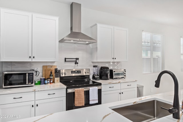 kitchen with wall chimney exhaust hood, white cabinetry, and appliances with stainless steel finishes