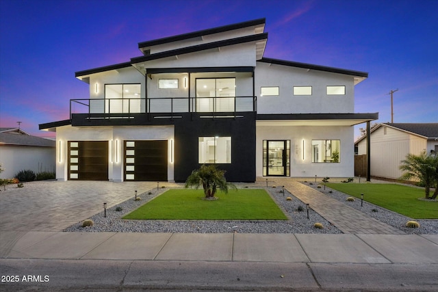 contemporary home with a yard, a garage, and a balcony