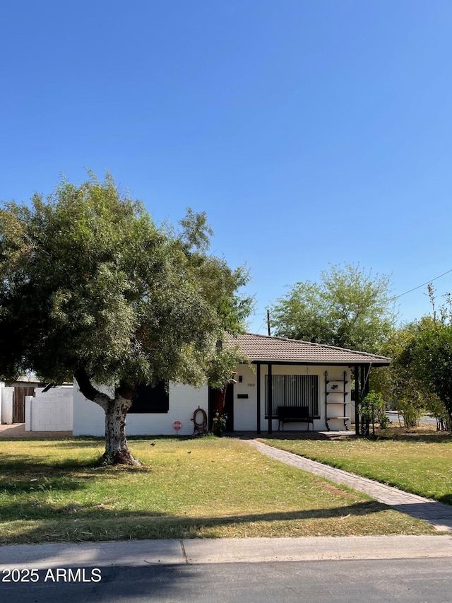 view of front of home featuring stucco siding, a front lawn, and fence