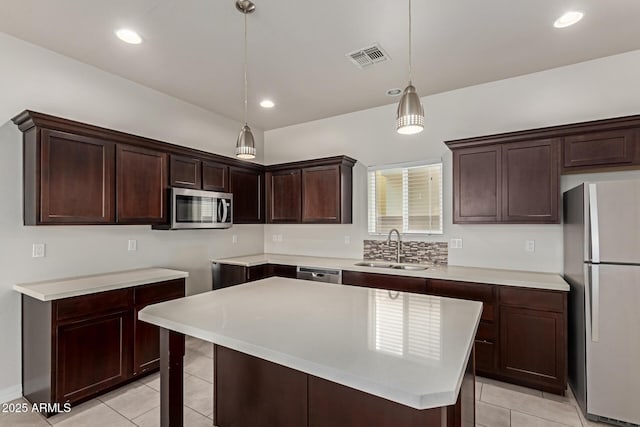 2000 N 36th St Unit 41, Phoenix, AZ 85008 - kitchen featuring stainless steel appliances, light tile patterned floors, dark brown cabinets, decorative light fixtures, and light countertops