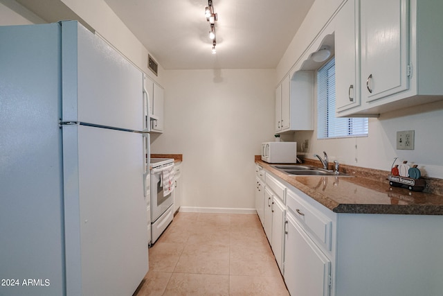 kitchen with track lighting, white appliances, sink, light tile patterned floors, and white cabinets