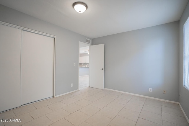 unfurnished bedroom with visible vents, baseboards, a closet, and light tile patterned flooring