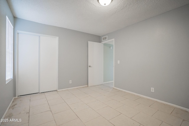 unfurnished bedroom with baseboards, visible vents, a closet, and a textured ceiling