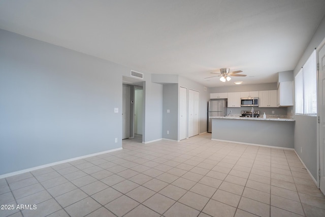 unfurnished living room with visible vents, baseboards, and ceiling fan