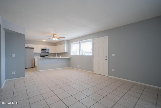 kitchen with baseboards, ceiling fan, appliances with stainless steel finishes, a peninsula, and white cabinetry