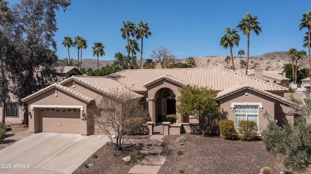 mediterranean / spanish home with driveway, an attached garage, stucco siding, a tile roof, and a mountain view