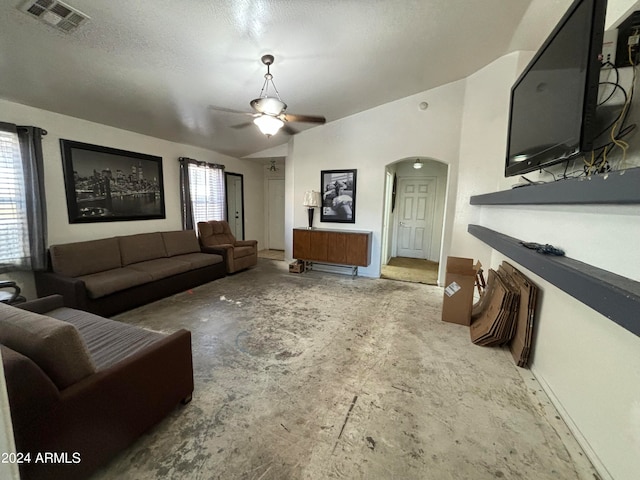 living room with a textured ceiling, ceiling fan, and lofted ceiling