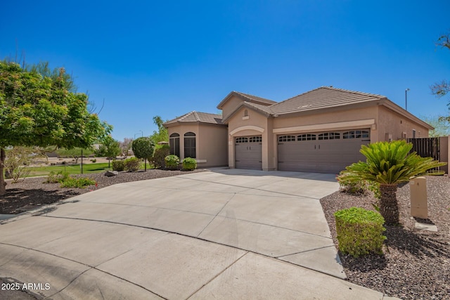 view of front of home featuring an attached garage, driveway, a tiled roof, and stucco siding