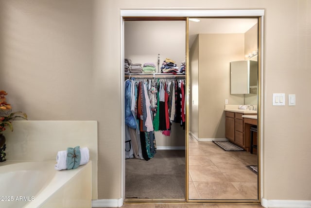 bathroom with vanity, a bath, a spacious closet, baseboards, and tile patterned flooring
