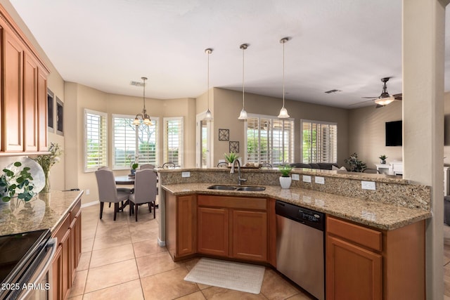 kitchen with stainless steel appliances, a sink, light tile patterned floors, and brown cabinetry