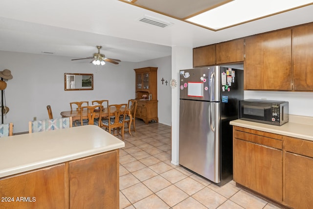 kitchen with stainless steel fridge, light tile patterned floors, and ceiling fan