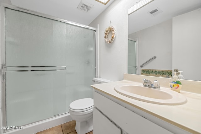 bathroom featuring tile patterned flooring, vanity, toilet, and a shower with shower door