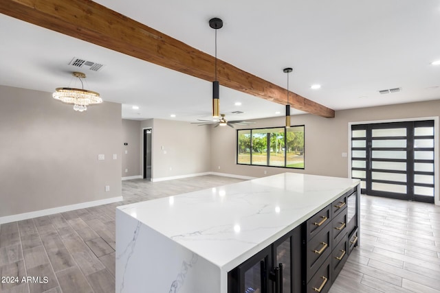 kitchen featuring a kitchen island, hanging light fixtures, light hardwood / wood-style floors, light stone counters, and beam ceiling