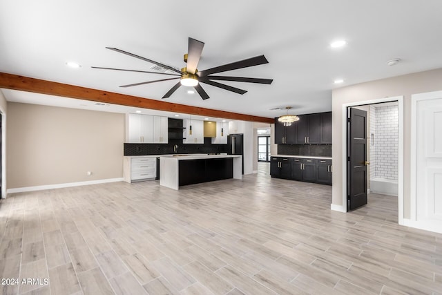 kitchen featuring a center island, beamed ceiling, ceiling fan with notable chandelier, decorative backsplash, and white cabinets