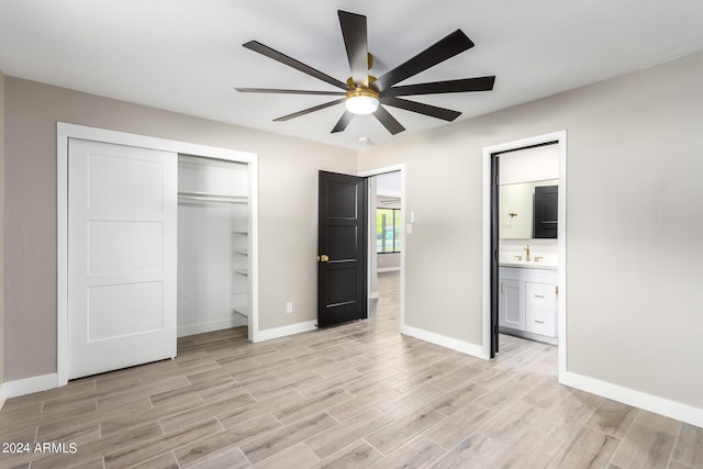 unfurnished bedroom featuring sink, ensuite bath, a closet, and light wood-type flooring