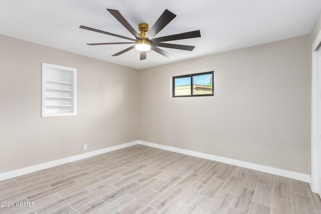 spare room featuring built in shelves, ceiling fan, and light hardwood / wood-style flooring