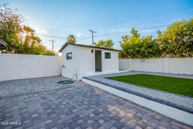 rear view of house with an outbuilding, a patio area, and a lawn