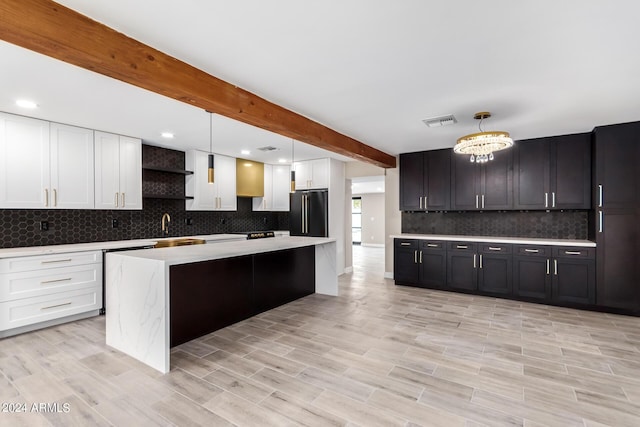 kitchen with high end fridge, beam ceiling, decorative backsplash, a kitchen island, and decorative light fixtures