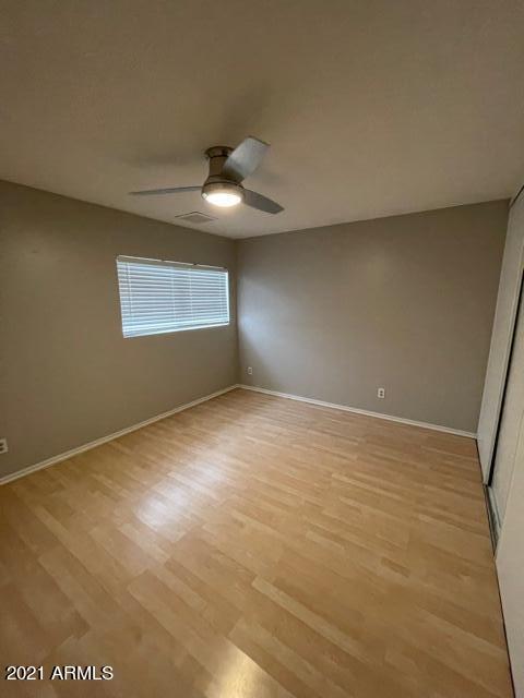 spare room featuring light wood-style floors, visible vents, baseboards, and a ceiling fan