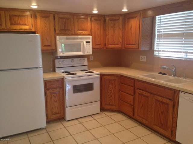 kitchen featuring light countertops, white appliances, and a sink