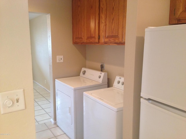 laundry room featuring washing machine and dryer, light tile patterned flooring, and cabinet space