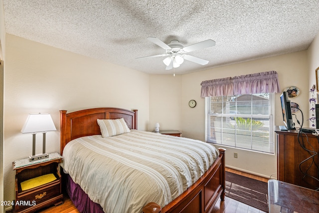 bedroom with a textured ceiling, light hardwood / wood-style flooring, and ceiling fan