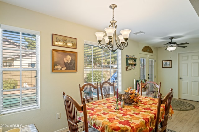 dining area featuring hardwood / wood-style floors, ceiling fan with notable chandelier, and french doors