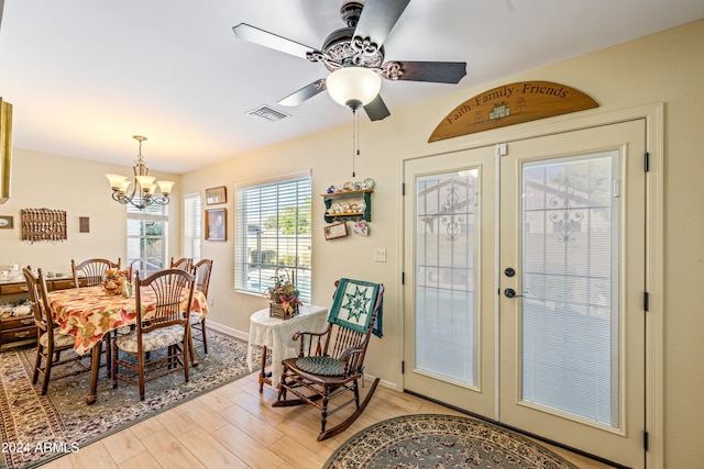 dining area with ceiling fan with notable chandelier, light hardwood / wood-style floors, and french doors