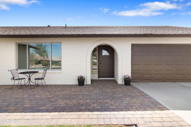 2329 S Elm, Mesa, AZ 85202 - view of exterior entry with concrete driveway, a shingled roof, brick siding, and a garage