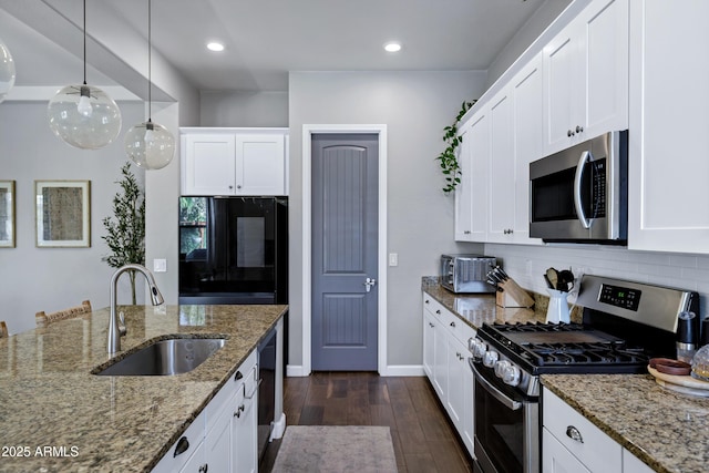 kitchen with appliances with stainless steel finishes, white cabinets, backsplash, a sink, and dark wood-type flooring