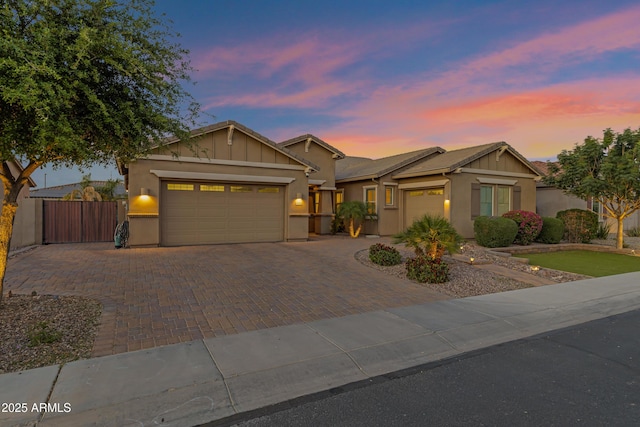 view of front facade featuring stucco siding, decorative driveway, fence, and a garage