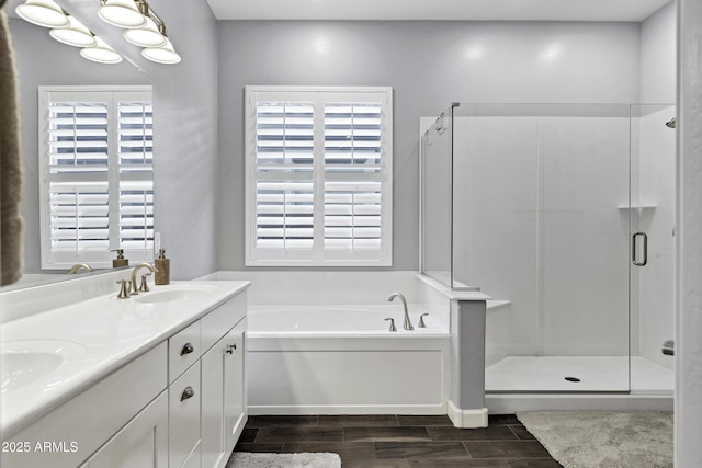 bathroom featuring a sink, a shower stall, wood tiled floor, double vanity, and a garden tub