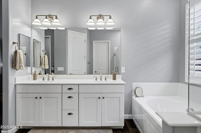 full bathroom featuring double vanity, wood finished floors, a bath, and a sink