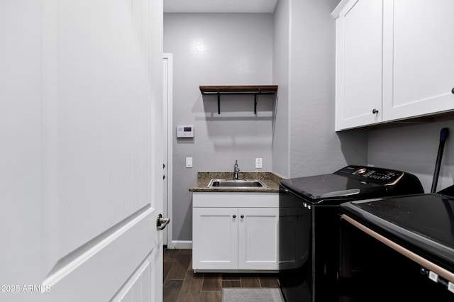 washroom with dark wood-style floors, a sink, cabinet space, baseboards, and washer and dryer