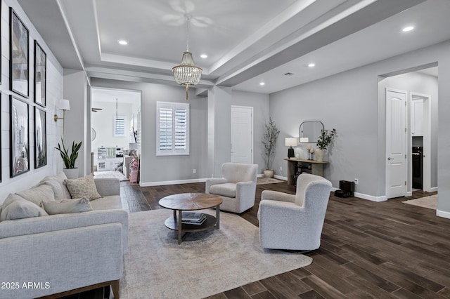 living room featuring dark wood-style flooring, a raised ceiling, recessed lighting, and baseboards
