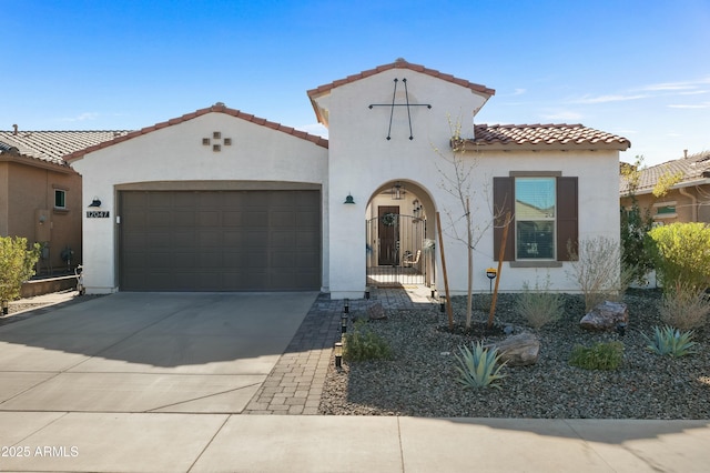 mediterranean / spanish house featuring a garage, a tile roof, concrete driveway, and stucco siding