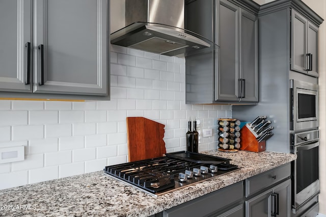 kitchen featuring wall chimney exhaust hood, appliances with stainless steel finishes, and gray cabinets