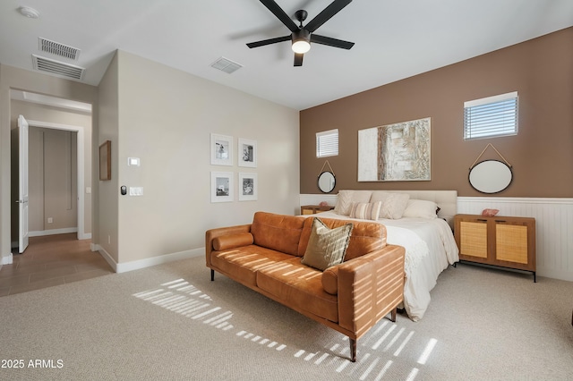 bedroom featuring ceiling fan, wainscoting, visible vents, and light colored carpet