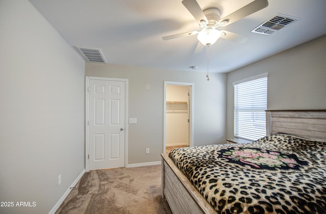 bedroom featuring a spacious closet, visible vents, light colored carpet, and baseboards